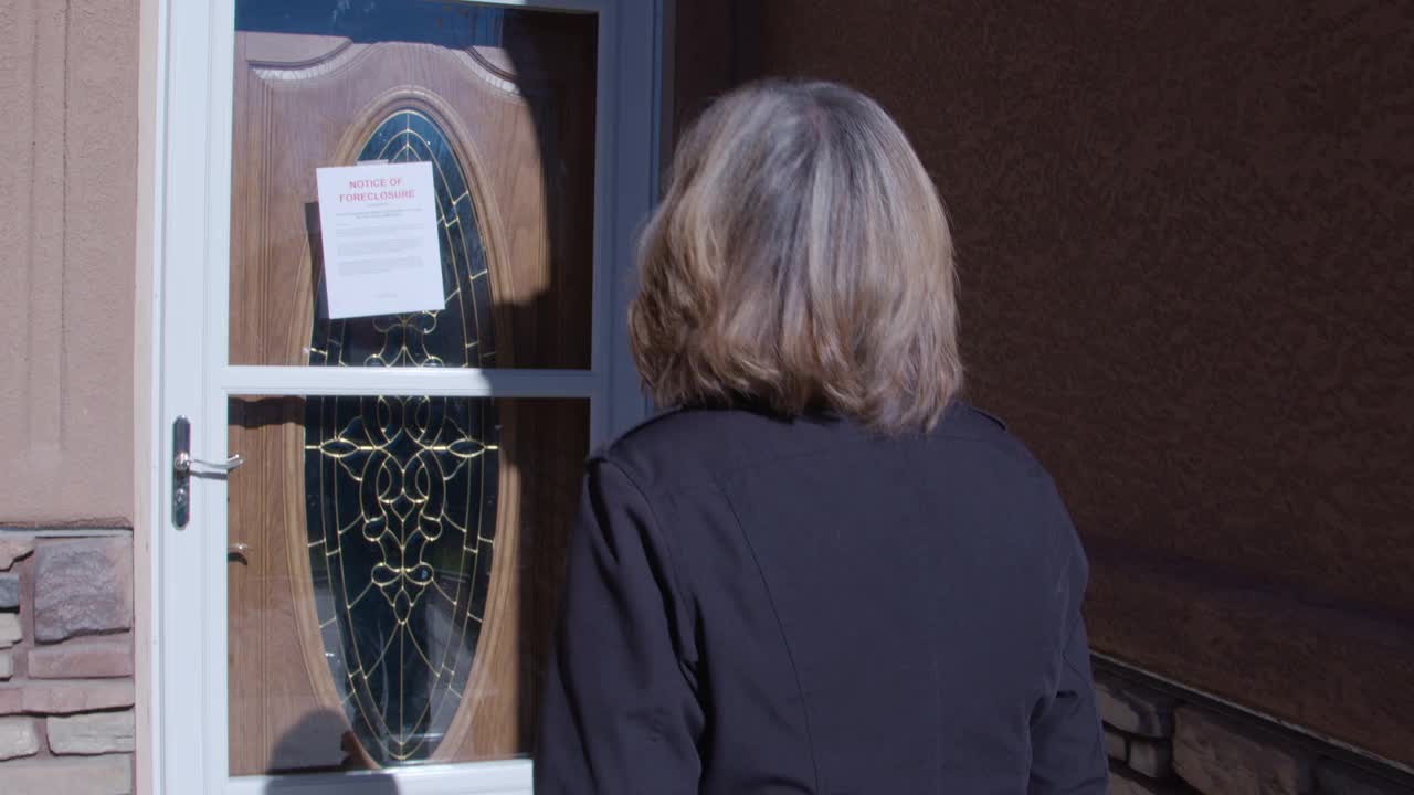 一位中年妇女看着贴在前门的止赎通知视频下载
