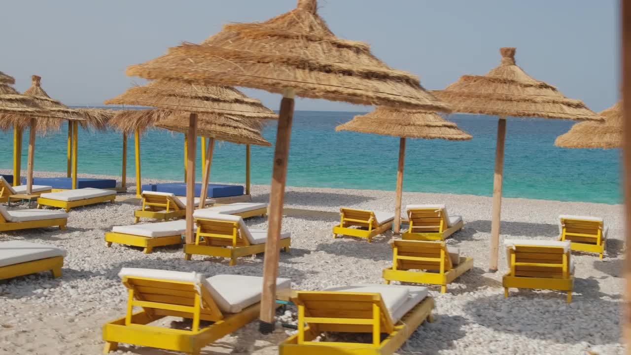 带着伞和日光浴床的相机慢慢地穿过美丽的海滩视频素材