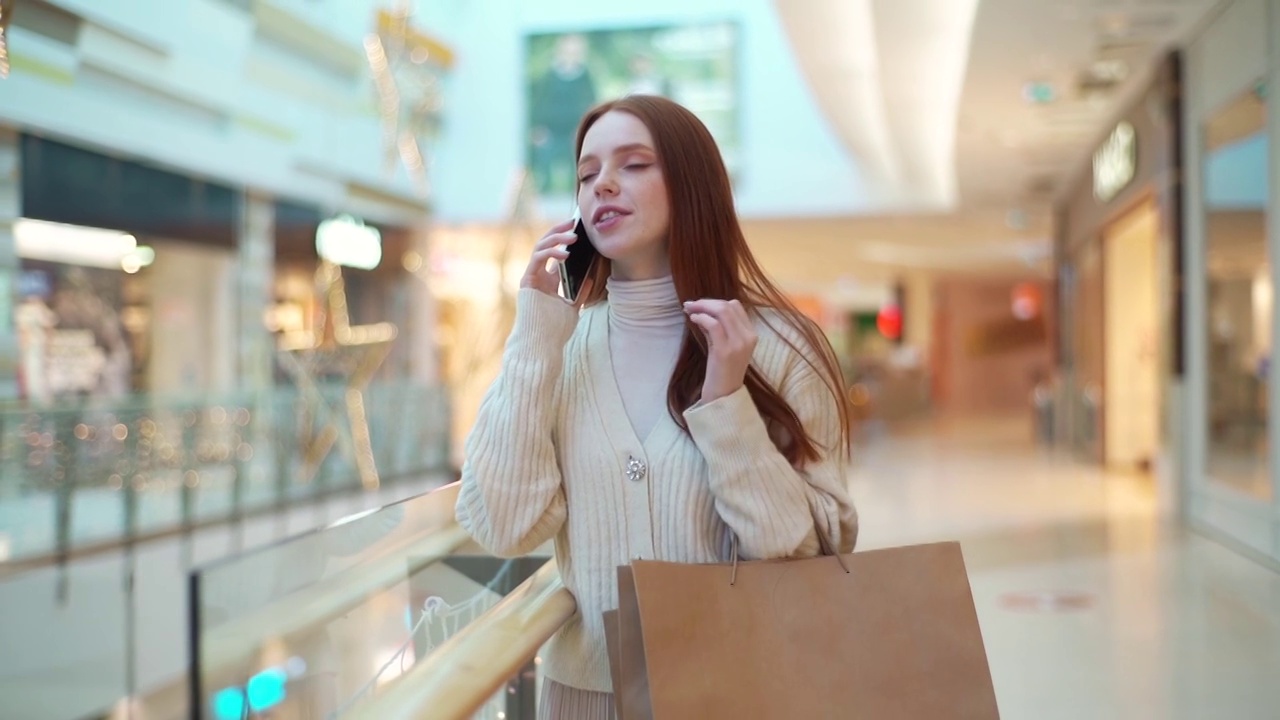 快乐的年轻女人的肖像拿着购物纸袋和与朋友交谈使用现代智能手机。视频素材