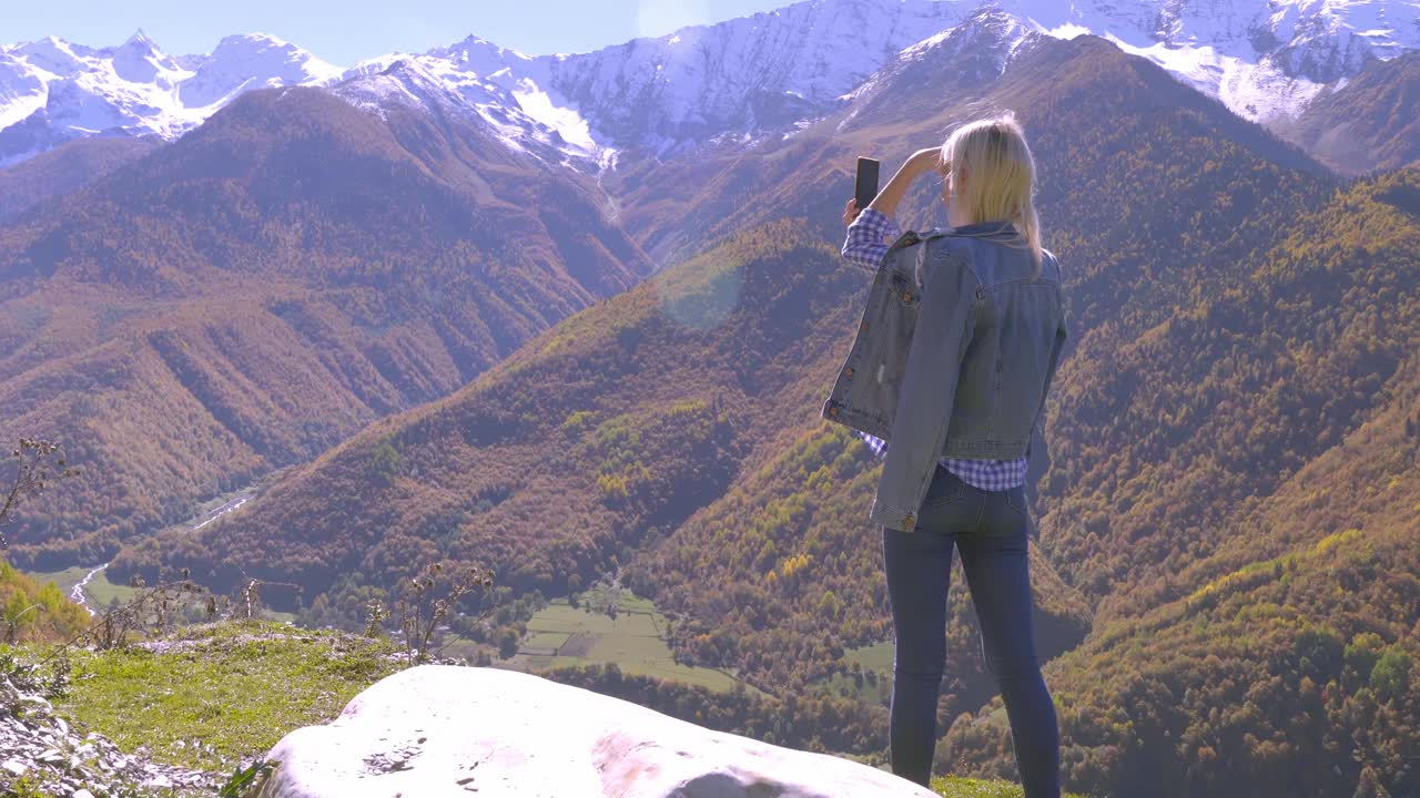 美丽的金发女郎拍摄秋天山上风景的照片或视频。视频素材
