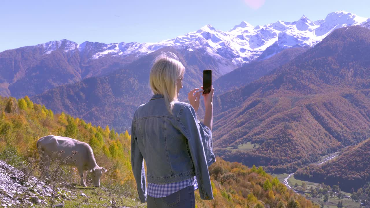 美丽的金发女郎拍摄秋天山上风景的照片或视频。视频素材