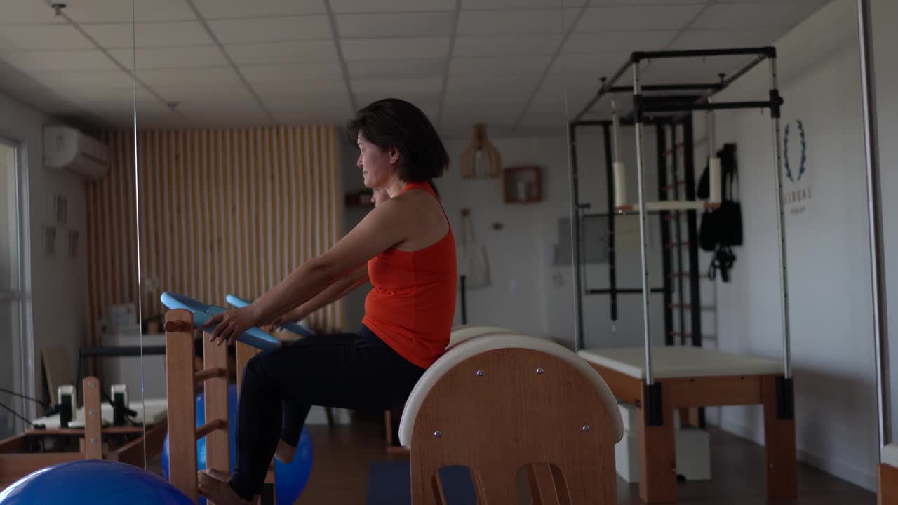 一个成熟的女人在普拉提工作室的木桶上锻炼视频素材