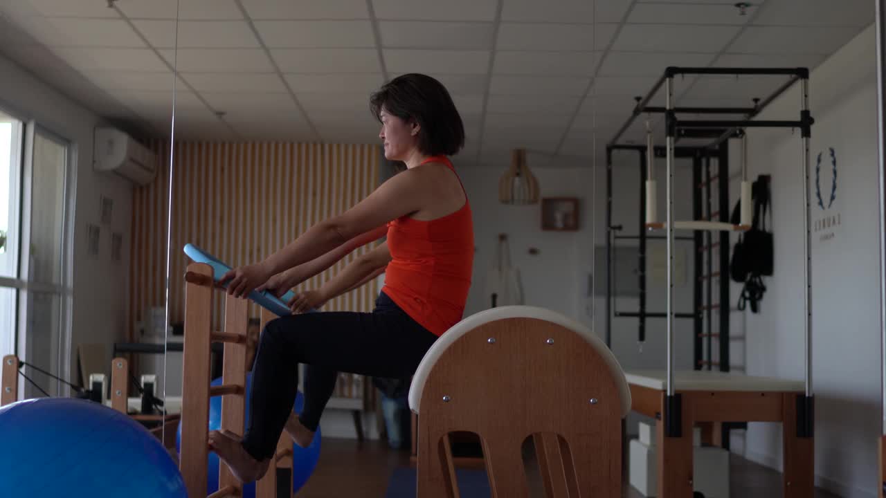 一个成熟的女人在普拉提工作室的木桶上锻炼视频素材