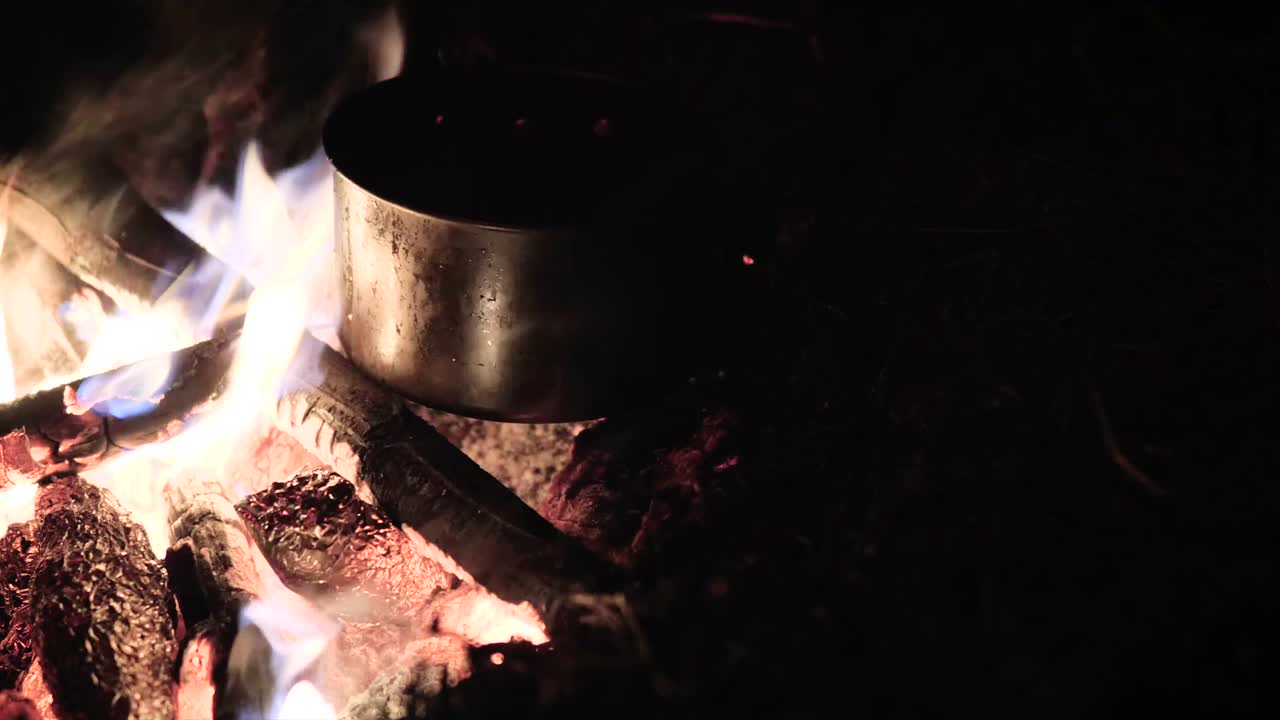 把一个水罐放在篝火在户外附近的山湖股票视频视频素材
