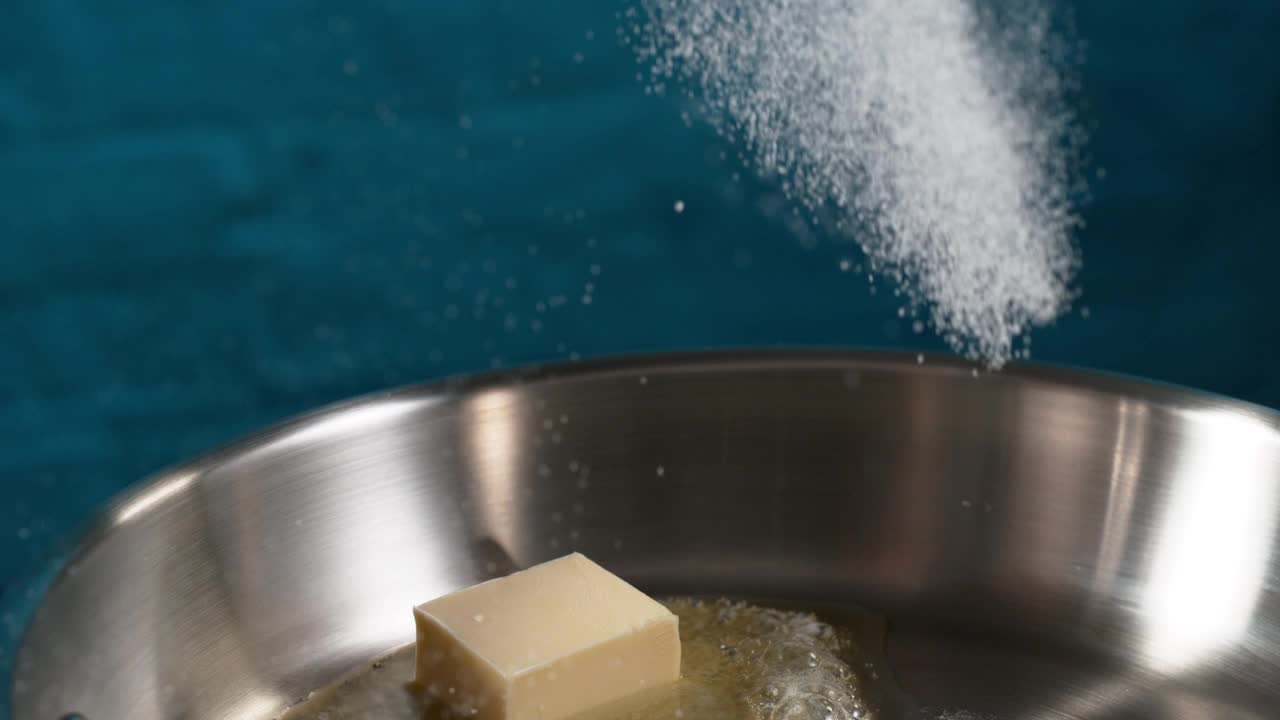 糖落在煎锅中融化的黄油上视频下载
