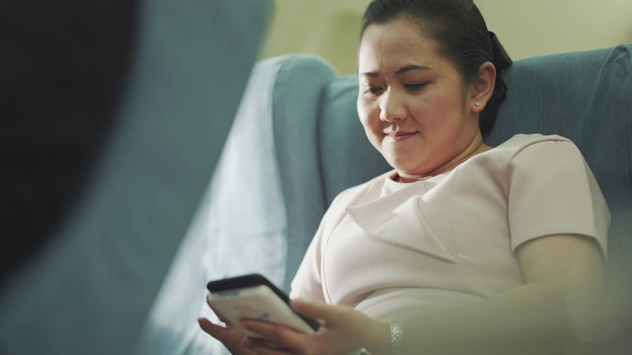 亚洲女性在飞机上使用智能手机视频下载