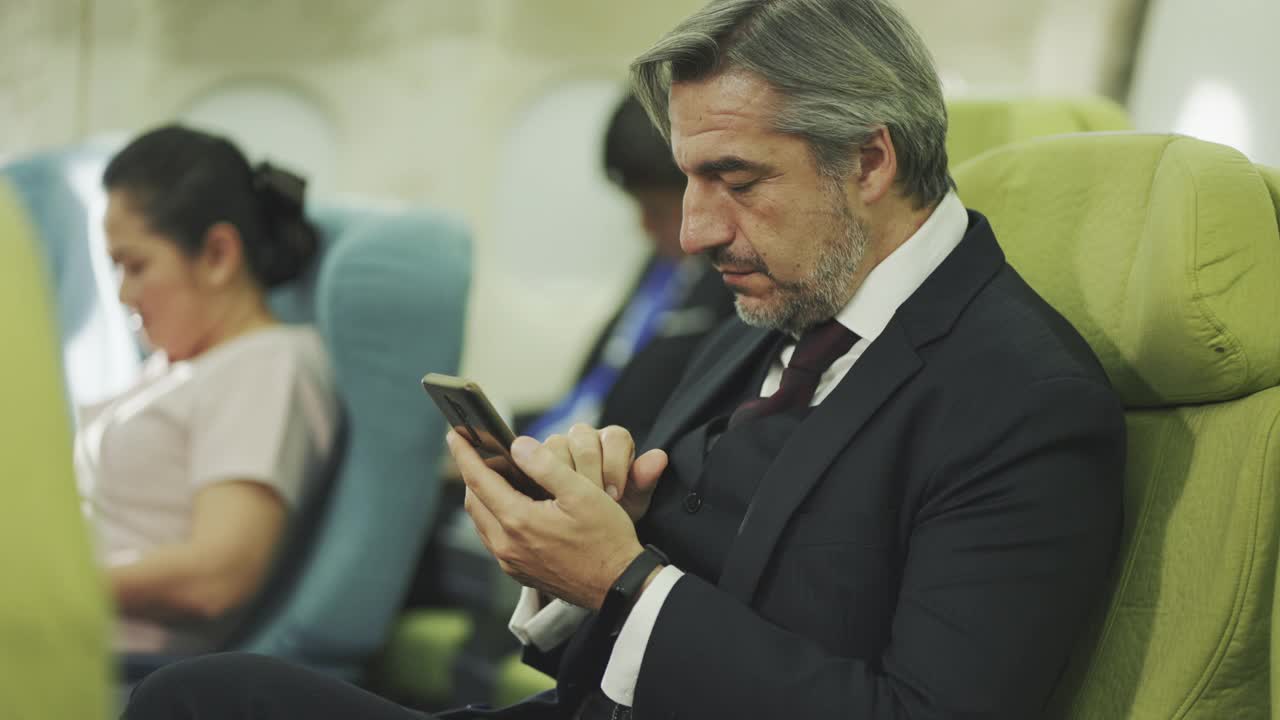 商人在飞机上使用智能手机视频下载