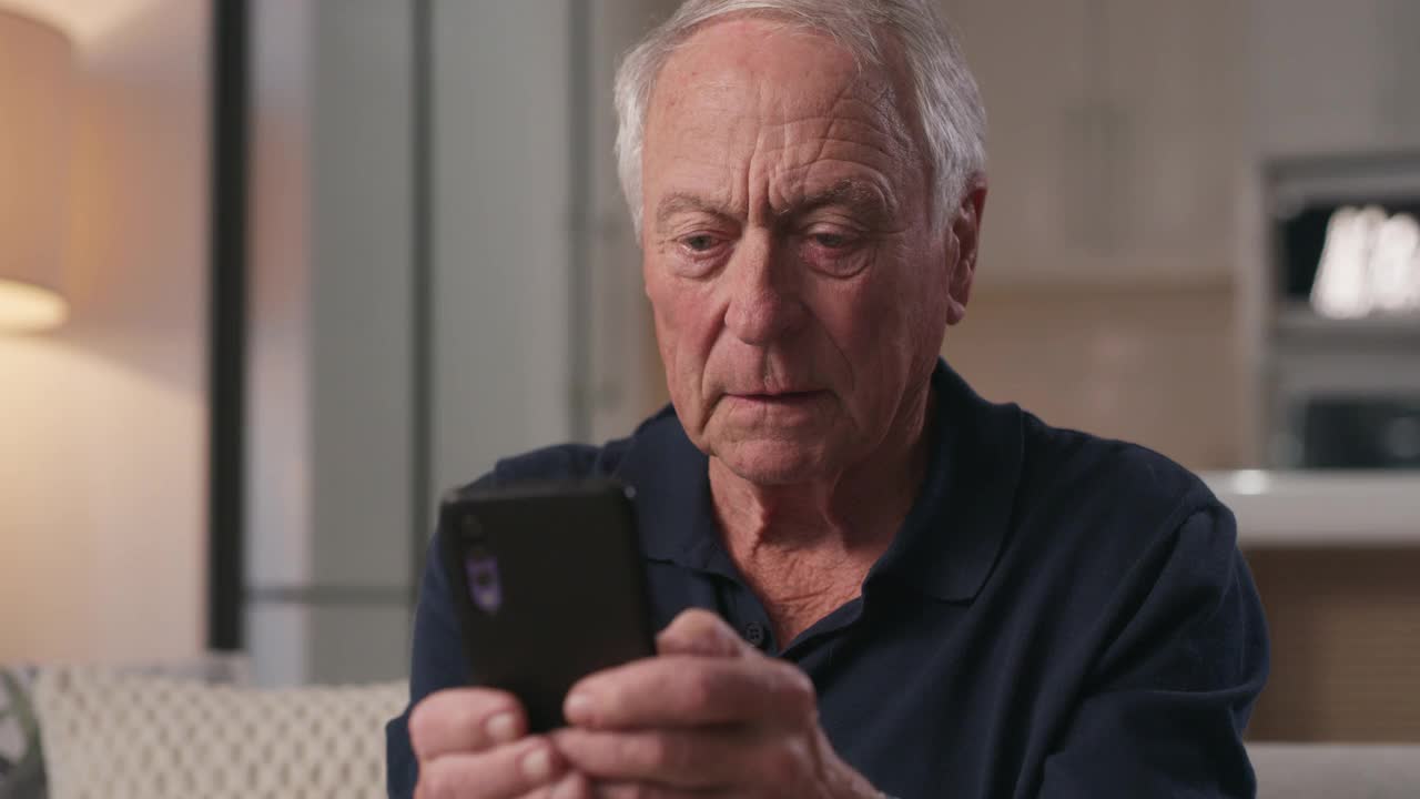 一名老年男性在家里用手机庆祝的4k视频视频下载