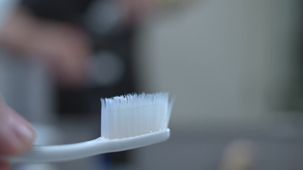 人的手挤压牙膏在牙刷上，特写视频下载