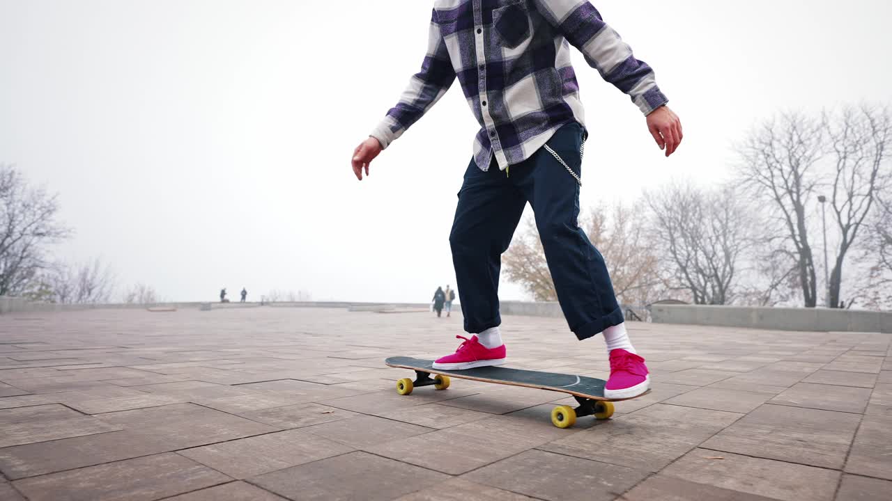 那家伙正在城市公园里骑长板。自由泳滑板风格。冰鞋在空中跳跃和翻转。用手保持平衡。慢动作，子弹时间视频素材