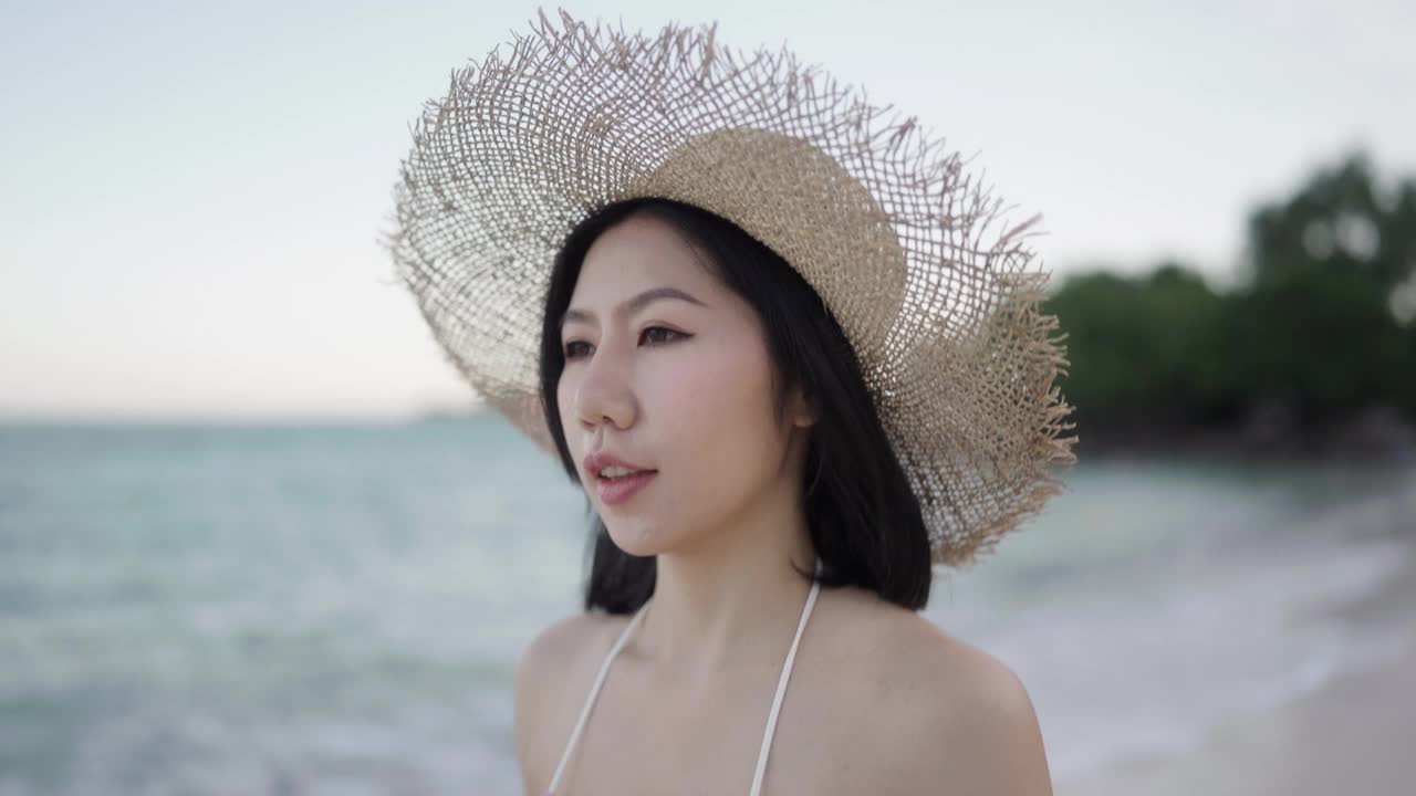 穿着比基尼的亚洲女人快乐地在海滩上散步。视频素材