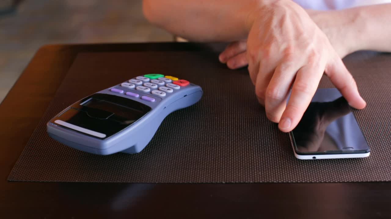 一名商人在餐厅用智能手机与NFC系统进行非接触交易视频下载