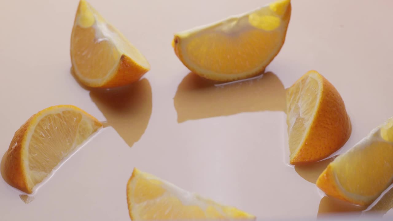 橙果和橙片一起慢慢地掉进橙汁里，溅出很多橙汁。视频素材