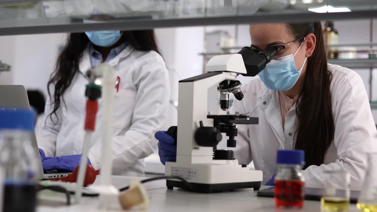 尊重新冠病毒防护措施的科学家们正在实验室进行实验。视频下载