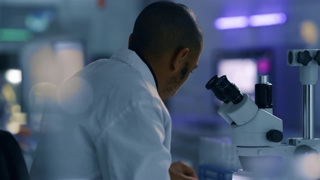 一个年轻人在实验室里使用显微镜的4k视频片段视频下载