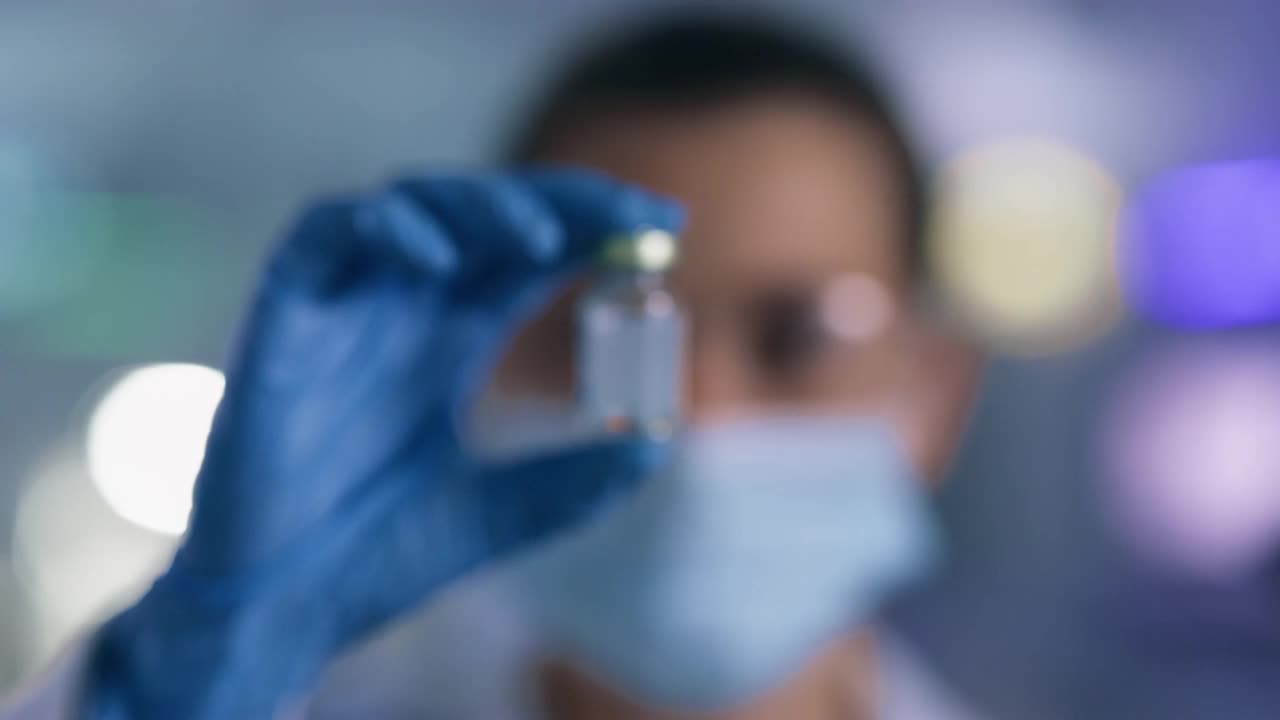 一个年轻科学家在实验室里拿着一个小瓶的4k视频片段视频素材