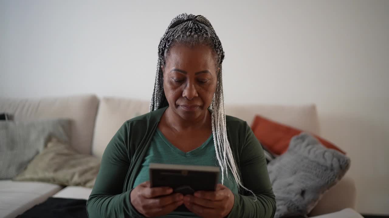 一位年长女性在家中看着思念某人的照片视频素材
