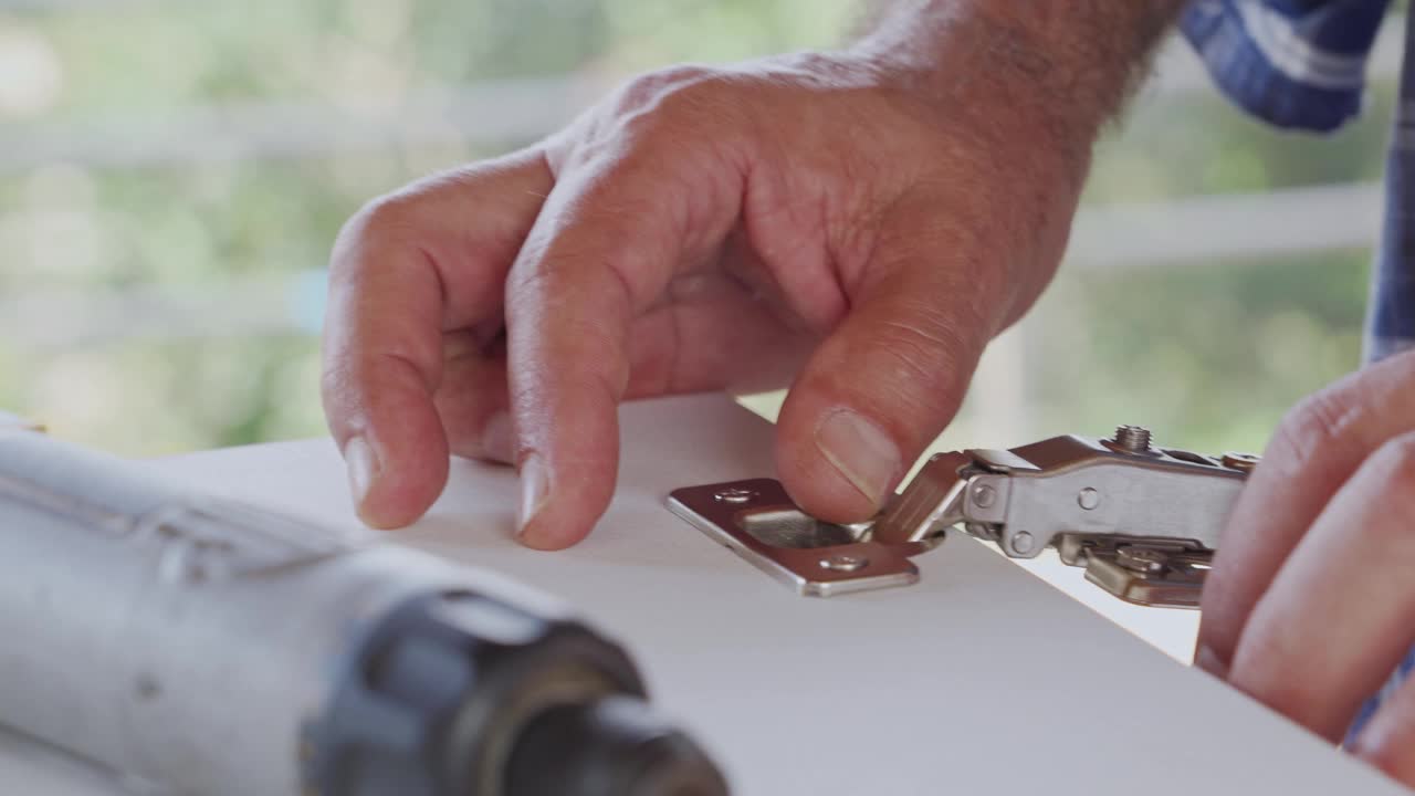 西班牙裔高级木匠安装门铰链在自己的房子厨房改造。视频下载