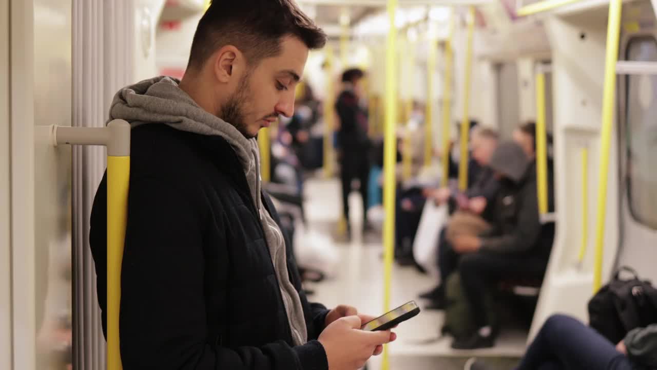 年轻人在地铁里打电话，用智能手机玩游戏，用手机发短信，用手机浏览社交媒体，用一只手玩游戏，戴着耳机听音乐视频素材