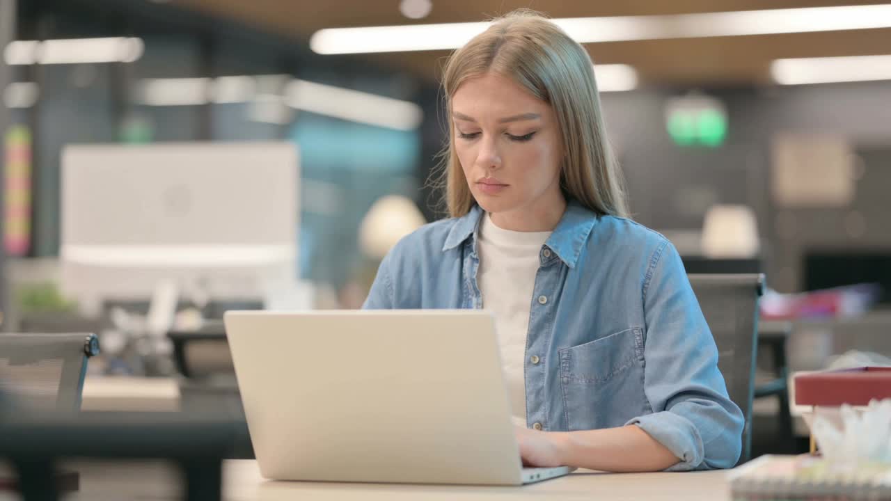年轻女性在办公时使用笔记本电脑时背部疼痛视频素材