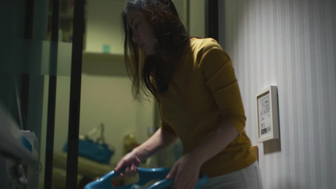 妇女工作家庭主妇在晚上工作后洗衣服视频素材