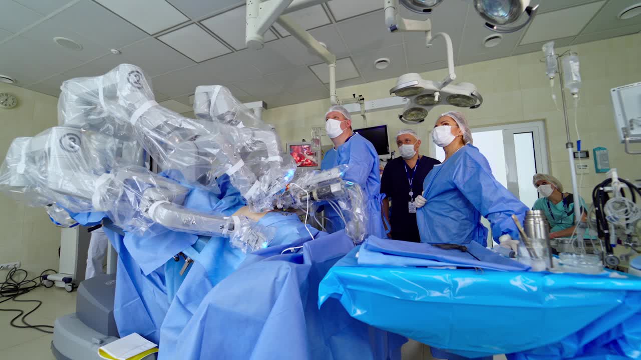 无菌手术室的机器人手术。一群医生在医院观察医疗机器人的工作。现代临床中的微创手术。视频下载