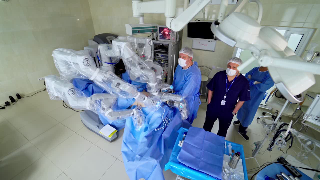 现代手术室中的机器人手术。在微创手术中，一群医疗专家站在机器人旁边。前视图。视频下载
