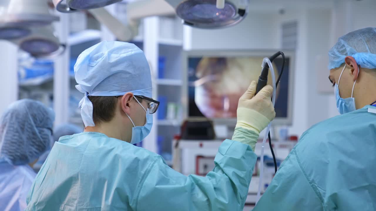 医疗团队背景上的大监视器。在现代化的手术室里，由专业的外科医生和助手进行外科手术。医生在医院外科手术中使用现代医疗设备。视频素材