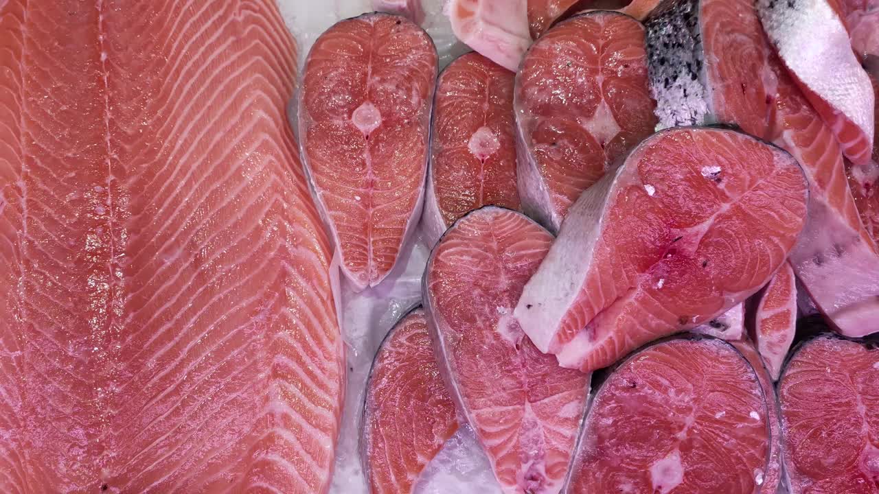 鱼片和大块的冷冻鲑鱼躺在商店的冰柜上视频下载
