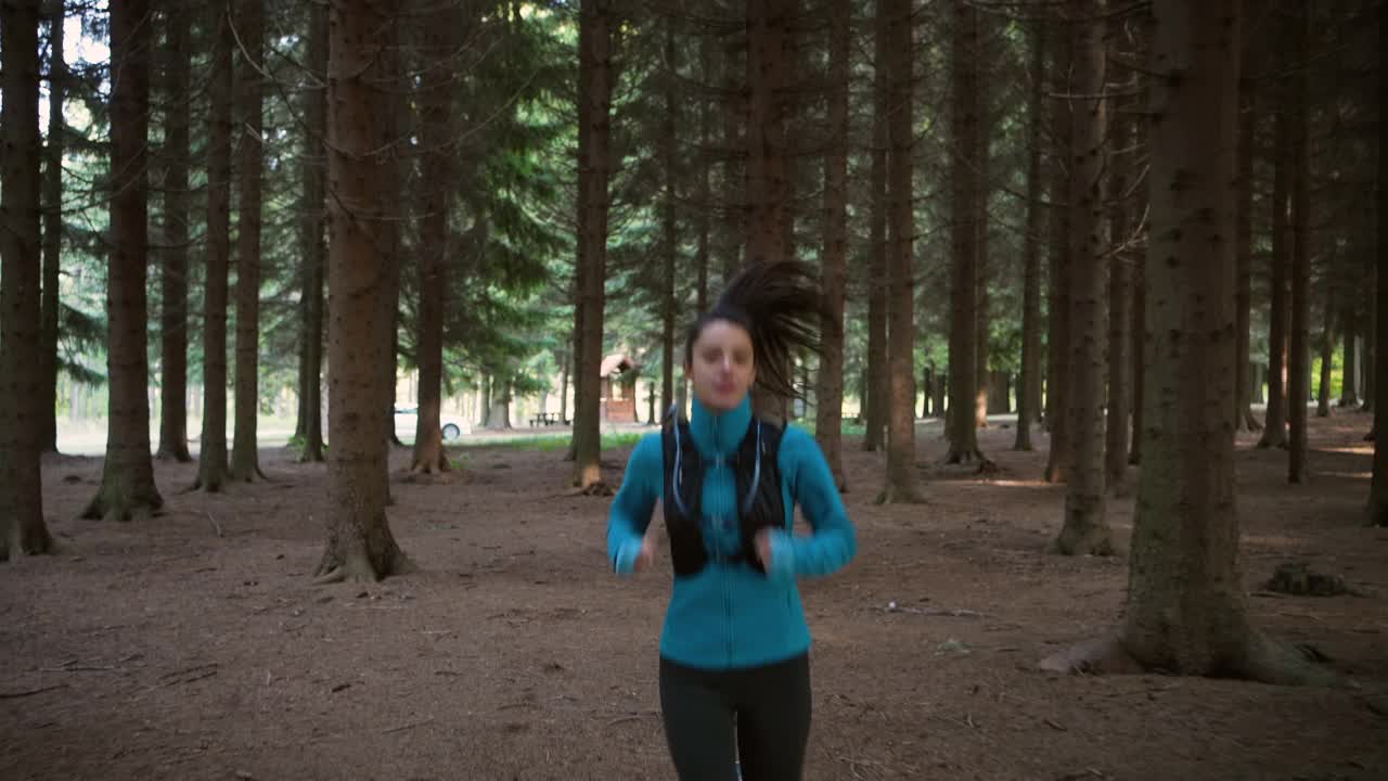 身着运动服的女越野运动员，在森林中奔跑视频素材