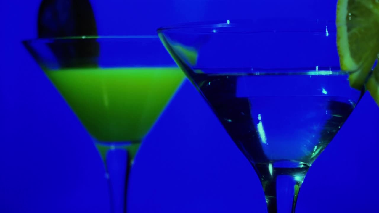 霓虹灯下，鸡尾酒迷人的玻璃杯在吧台上旋转视频素材