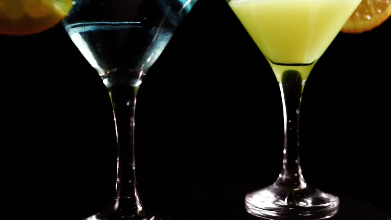 迷人的玻璃杯与鸡尾酒旋转在吧台上的黑色背景视频素材