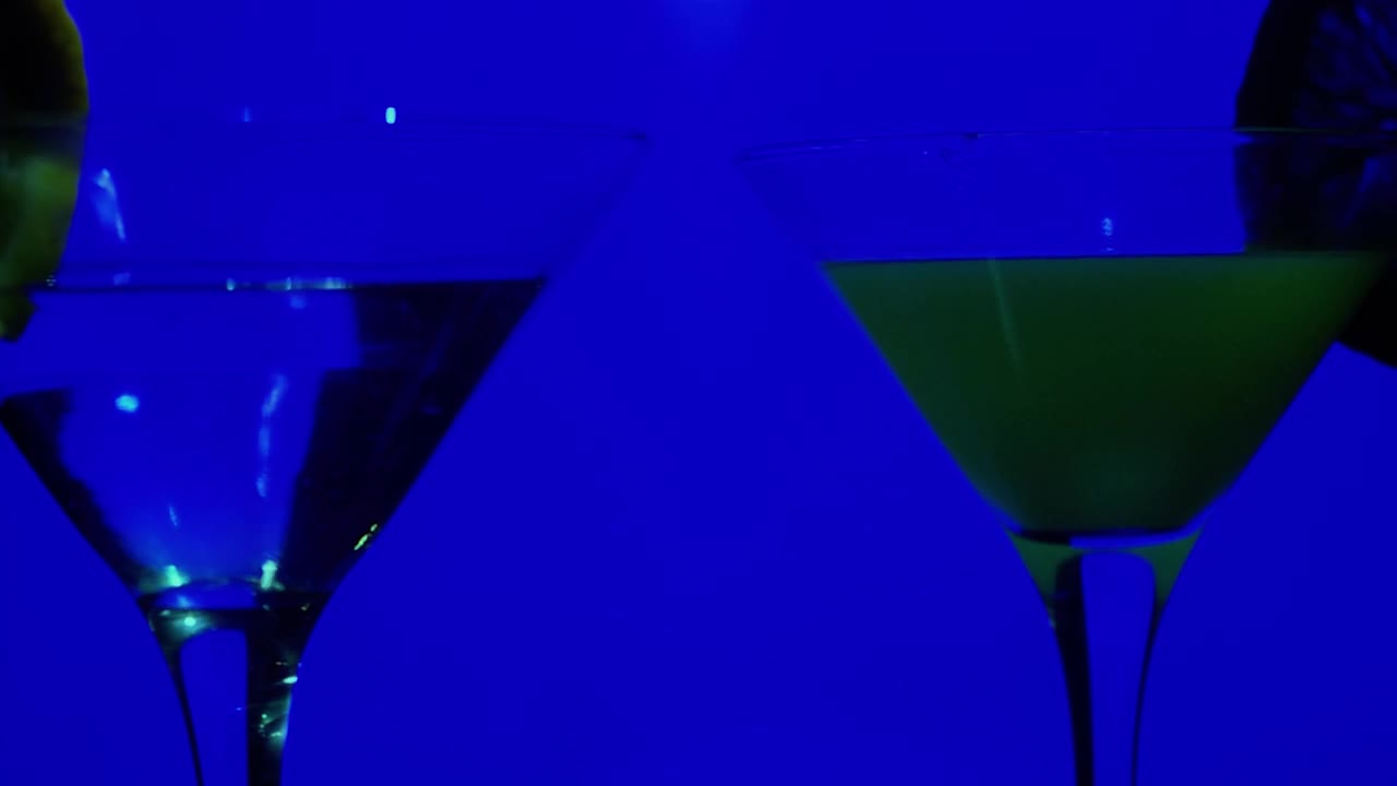 霓虹灯下，鸡尾酒迷人的玻璃杯在吧台上旋转视频素材
