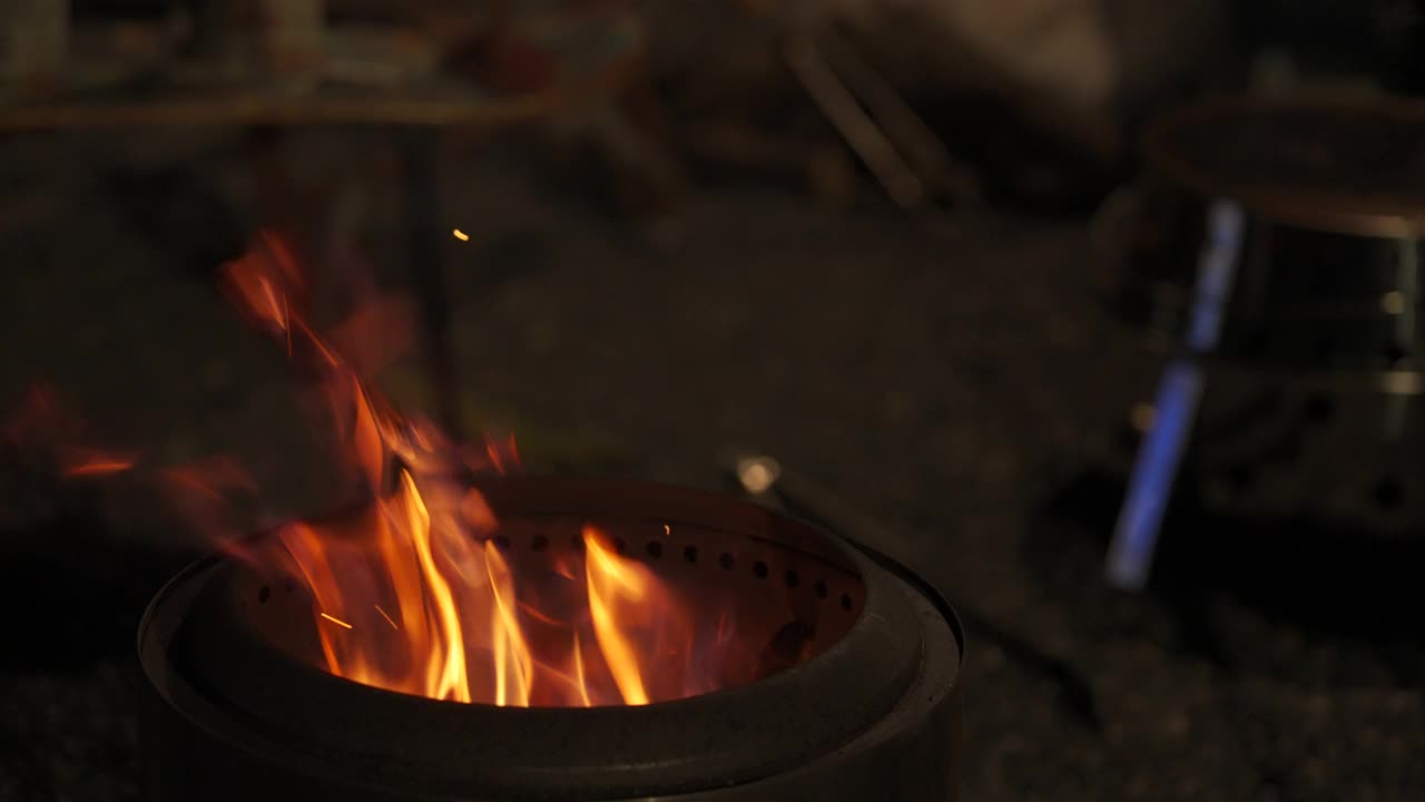 把柴火放在篝火炉里，晚上在露营地，冬季露营。视频下载
