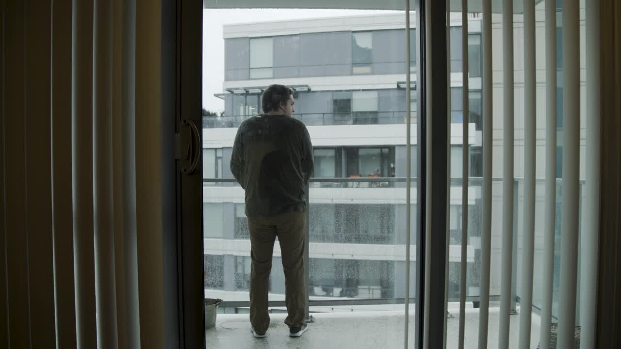 一个白人男子在他公寓的阳台上视频素材