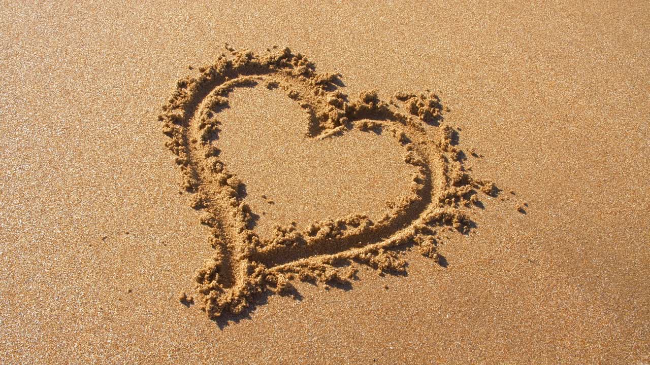 爱情的心放在沙滩上，被沙滩上的沙子冲掉，被海浪冲走。视频下载