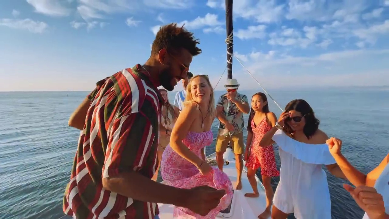 日落时分，一男一女和一群朋友在游艇上跳舞视频素材