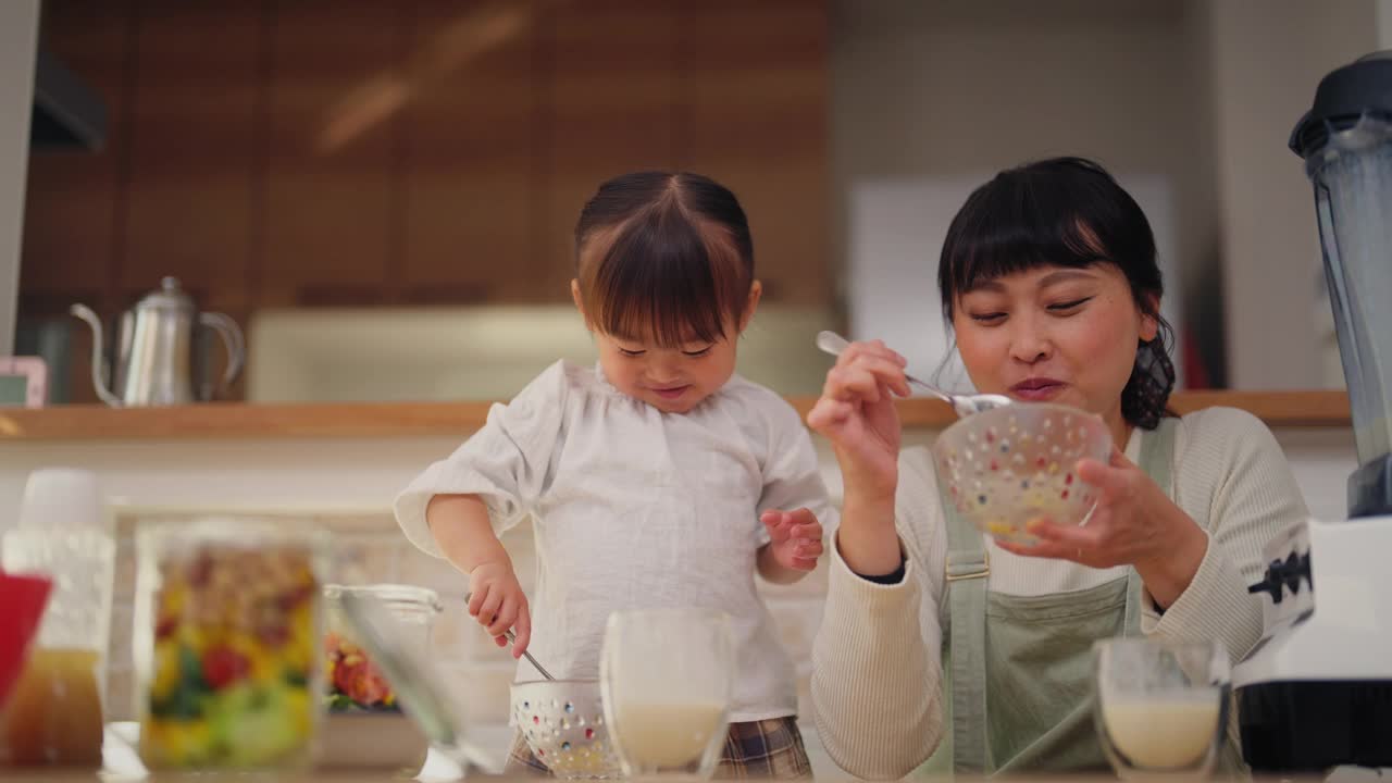 妈妈和她的小女儿喜欢在家吃沙拉和喝奶昔视频素材