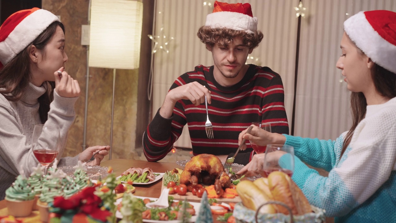一群多种族的年轻人在家里一起吃着鸡肉圣诞晚餐视频素材