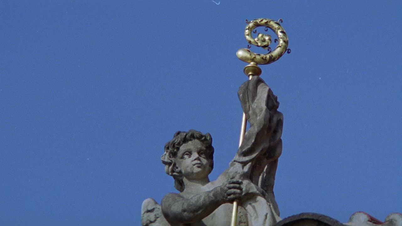 向上角的石头小天使抱着金杖。雕像和雕塑。可能是檐口或建筑物的屋顶。放大脸部。视频下载