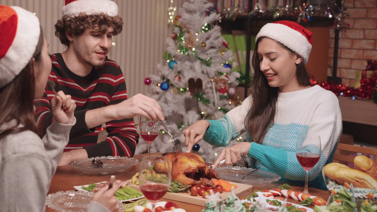 美丽的亚洲女人有乐趣当切碎鸡肉给美国朋友在家里圣诞派对视频下载