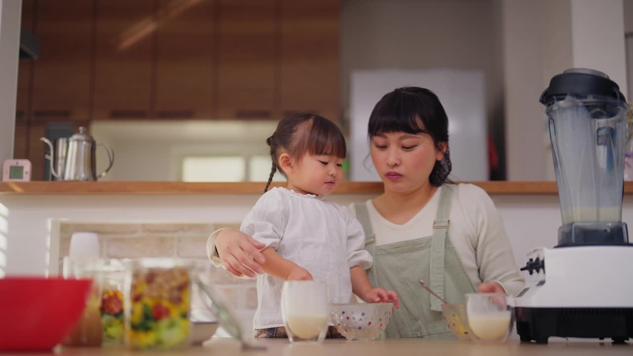 妈妈和她的小女儿喜欢在家吃沙拉和喝奶昔视频素材