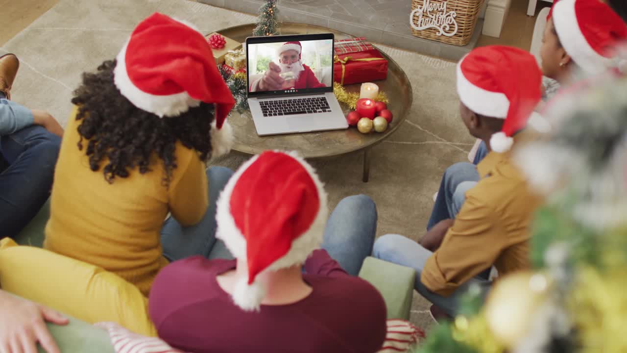 不同的家庭戴着圣诞帽，用笔记本电脑进行圣诞视频通话，屏幕上显示快乐的圣诞老人视频下载