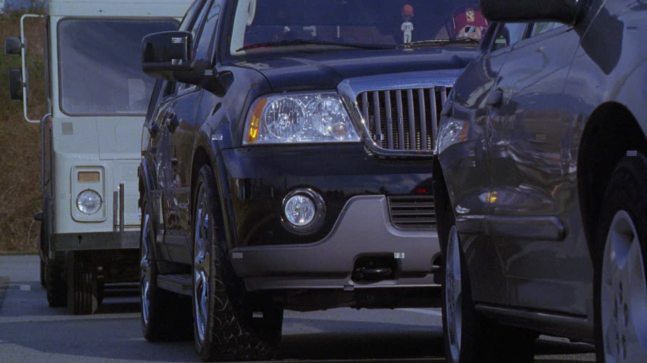 一辆大型运动型多用途车的前保险杠的近角度与闪亮的铬合金轮毂盖或轮辋卡在交通中。视频下载