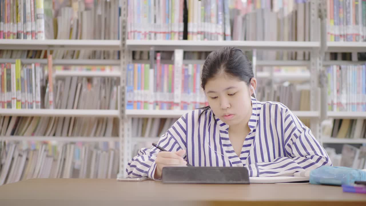 亚洲少女在图书馆在线工作视频素材