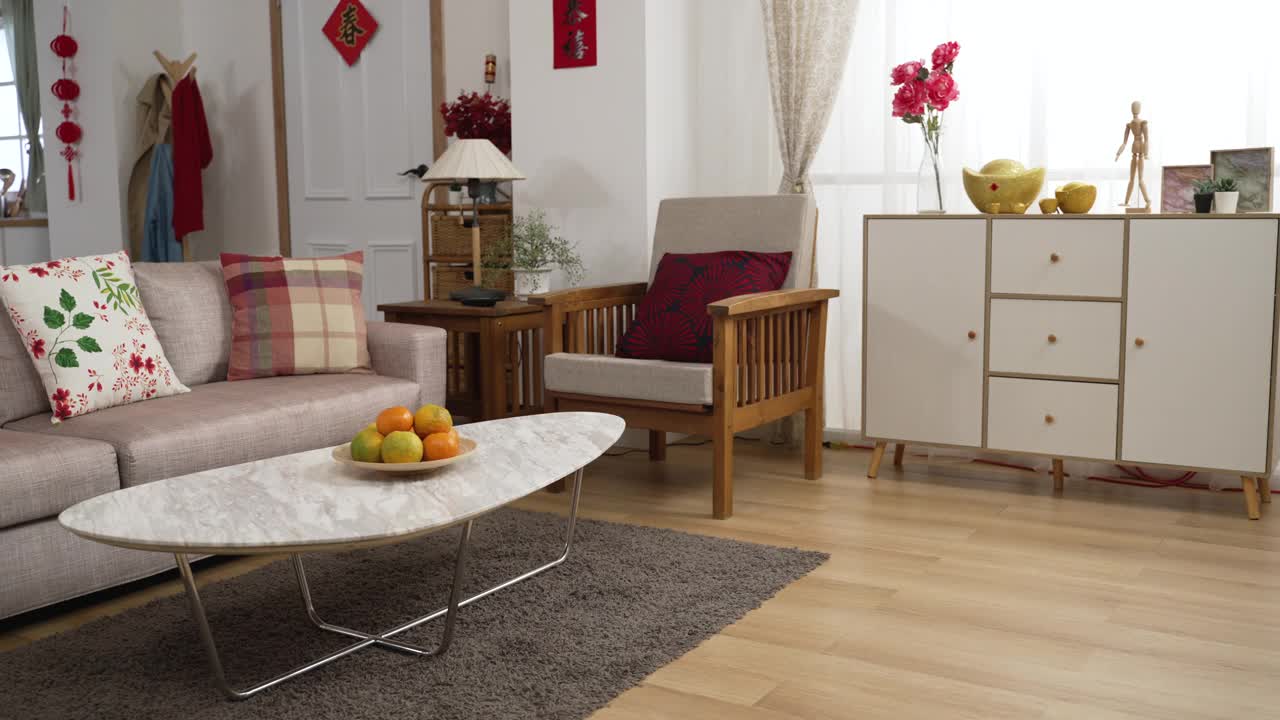 现代住宅室内与沙发和桔子在客厅的桌子上庆祝中国农历新年。门上字译:新春贺喜视频下载