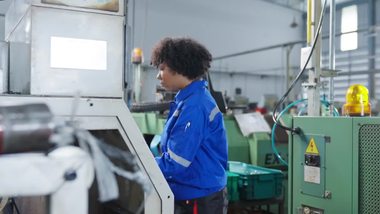 女性非裔美籍机械工程师操作数控铣床的安装过程，女性技术员工作在生产金属产品的进度线视频素材