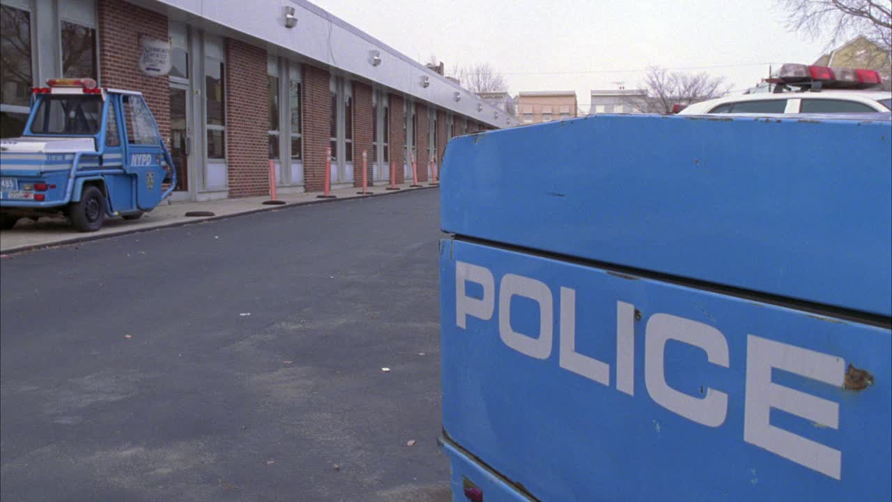 广角低处的警察局或一层砖砌建筑，前方有“警察”车。警车横档可见。背景是多层公寓楼。纽约警察局。视频素材