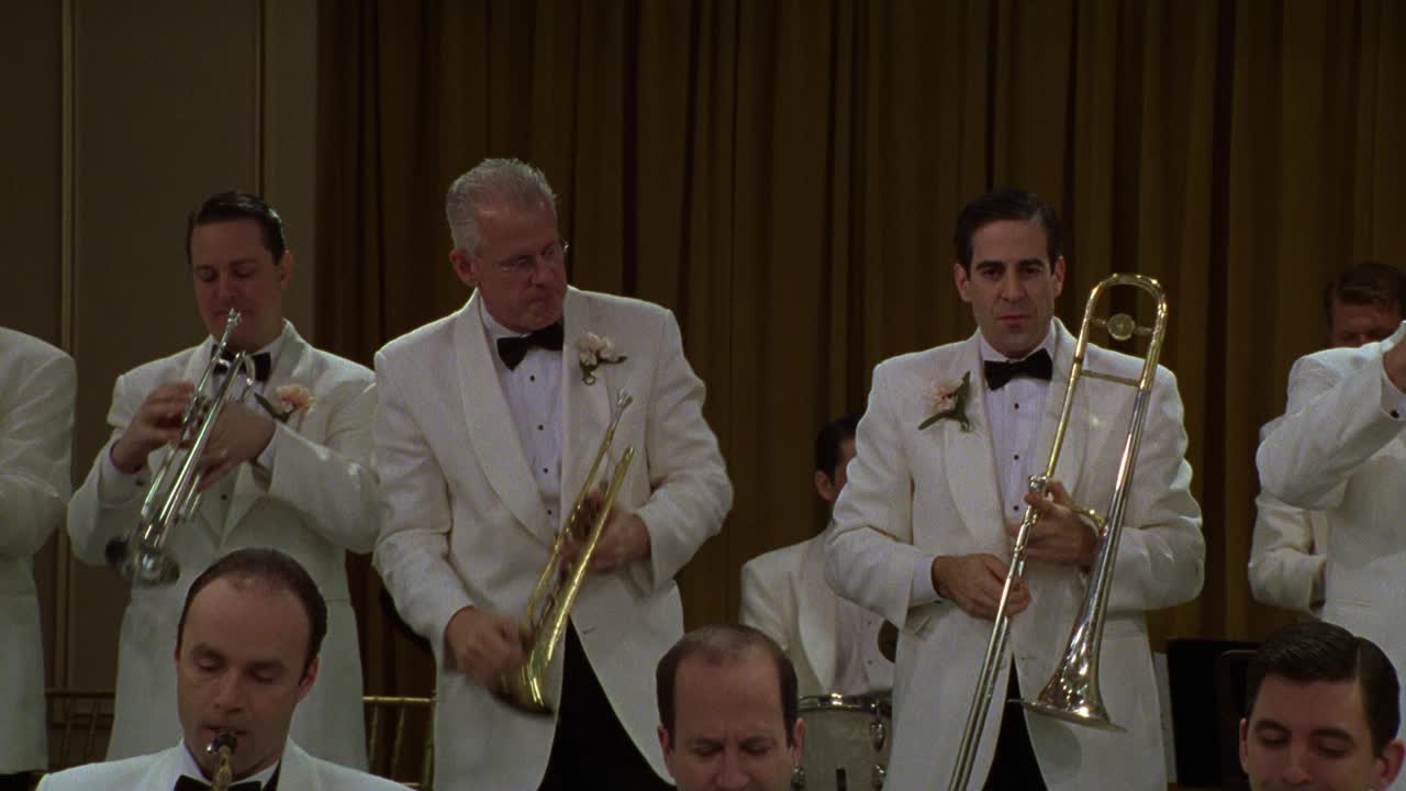 许多音乐家在一个大乐队里从右到左。他们穿着白色的西装，演奏铜管乐器。可能是在餐厅、酒店或舞厅。视频下载