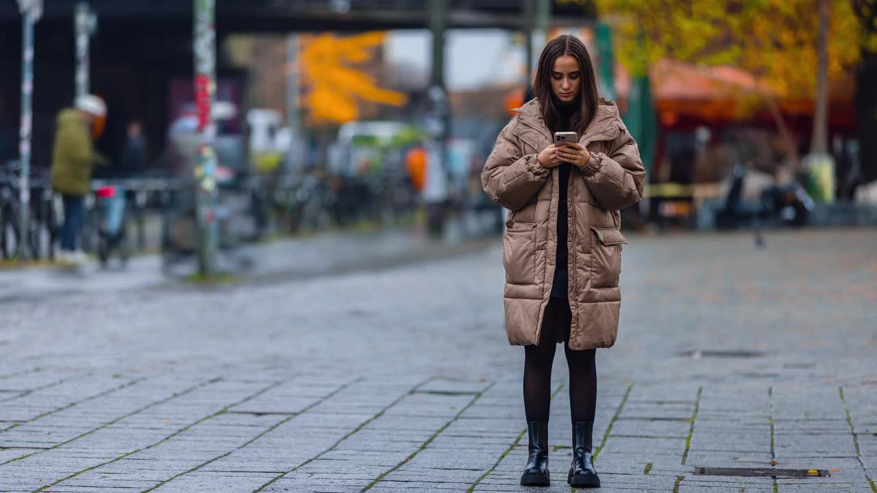 年轻女性在公共街道上用智能手机浏览社交媒体、查看新闻、玩手机游戏或发短信的时间流逝。视频下载